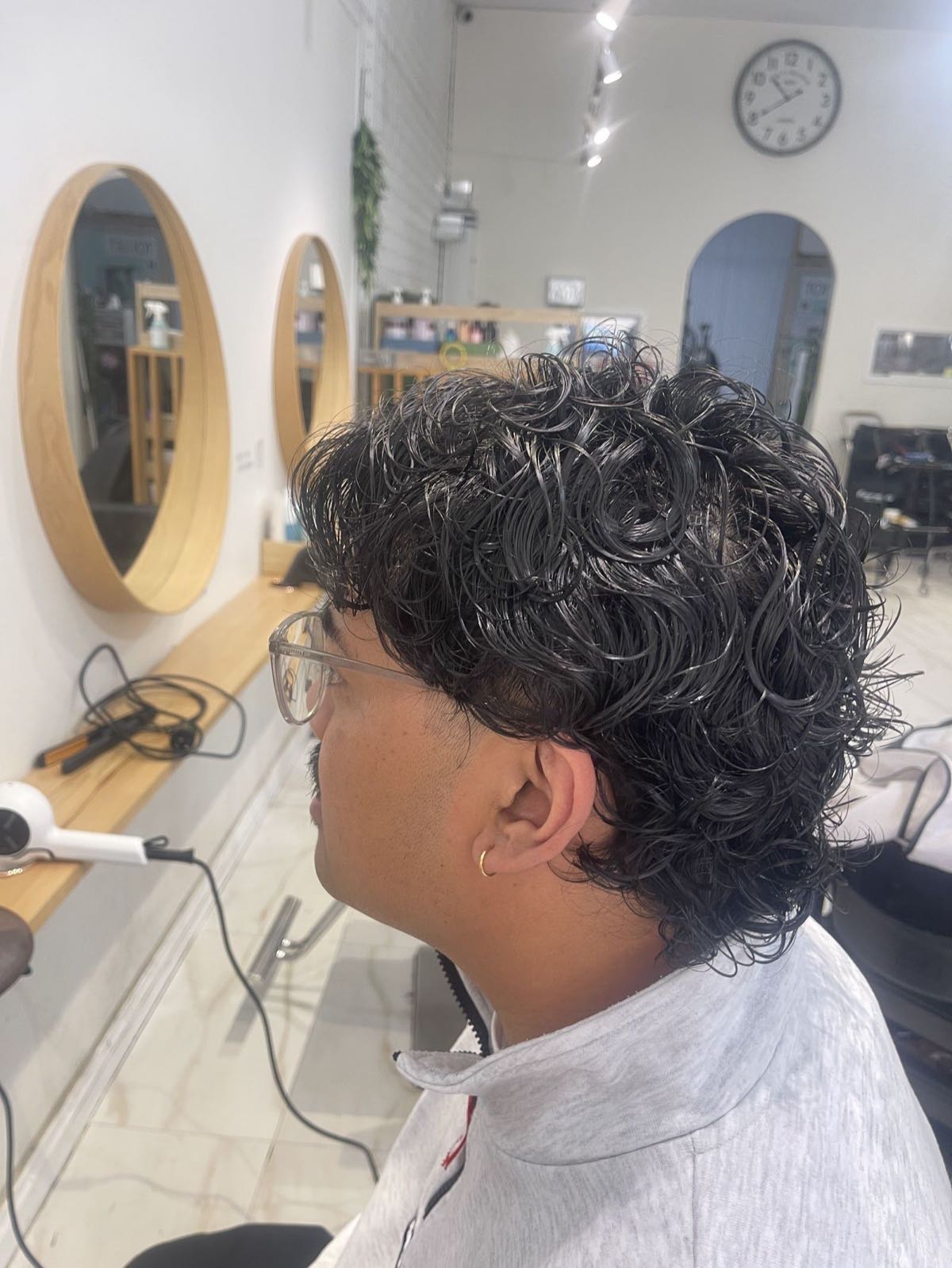 Client with a fresh Korean perm inside the K Hair Lab salon, round wooden mirrors behind